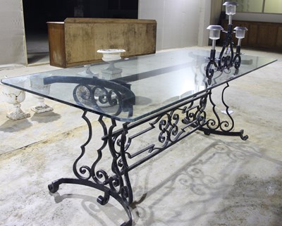 Lot 700 - A large glass top table with a wrought iron...