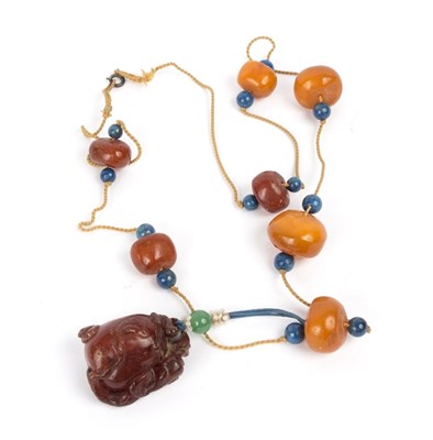 Lot 146 - A Chinese carved amber pendant modelled as a...