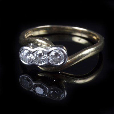 Lot 179 - A three-stone diamond ring, in a crossover...