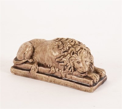 Lot 275 - A brown glazed figure of a recumbent lion, on...