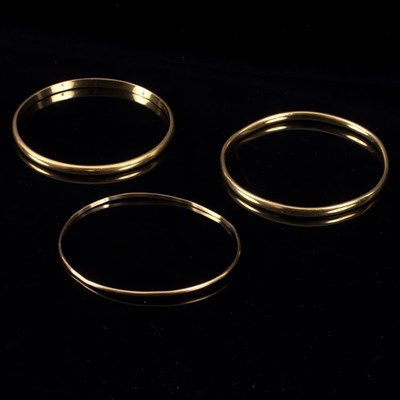 Lot 12 - Two 18ct yellow gold bangles and a 9ct bangle,...