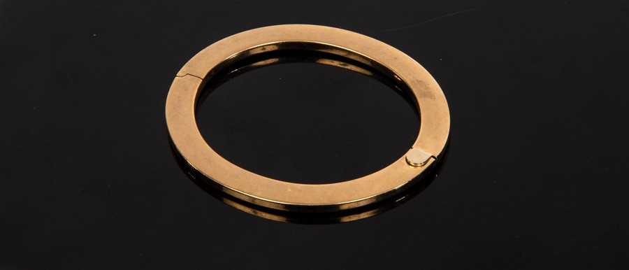 Lot 8 - A 9ct yellow gold hinged bangle of flattened...