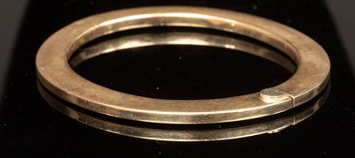 Lot 8 - A 9ct yellow gold hinged bangle of flattened...