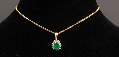 Lot 9 - An emerald and diamond cluster pendant on a...