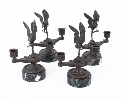 Lot 881 - A set of four patinated bronze two-branch candlesticks