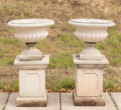 Lot 509 - A pair of composition stone urns on square plinths